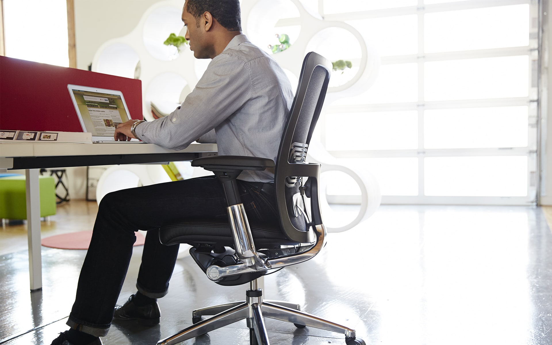 Man sits on black Haworth office chair Zody by ITO Design and works in stylish, bright office