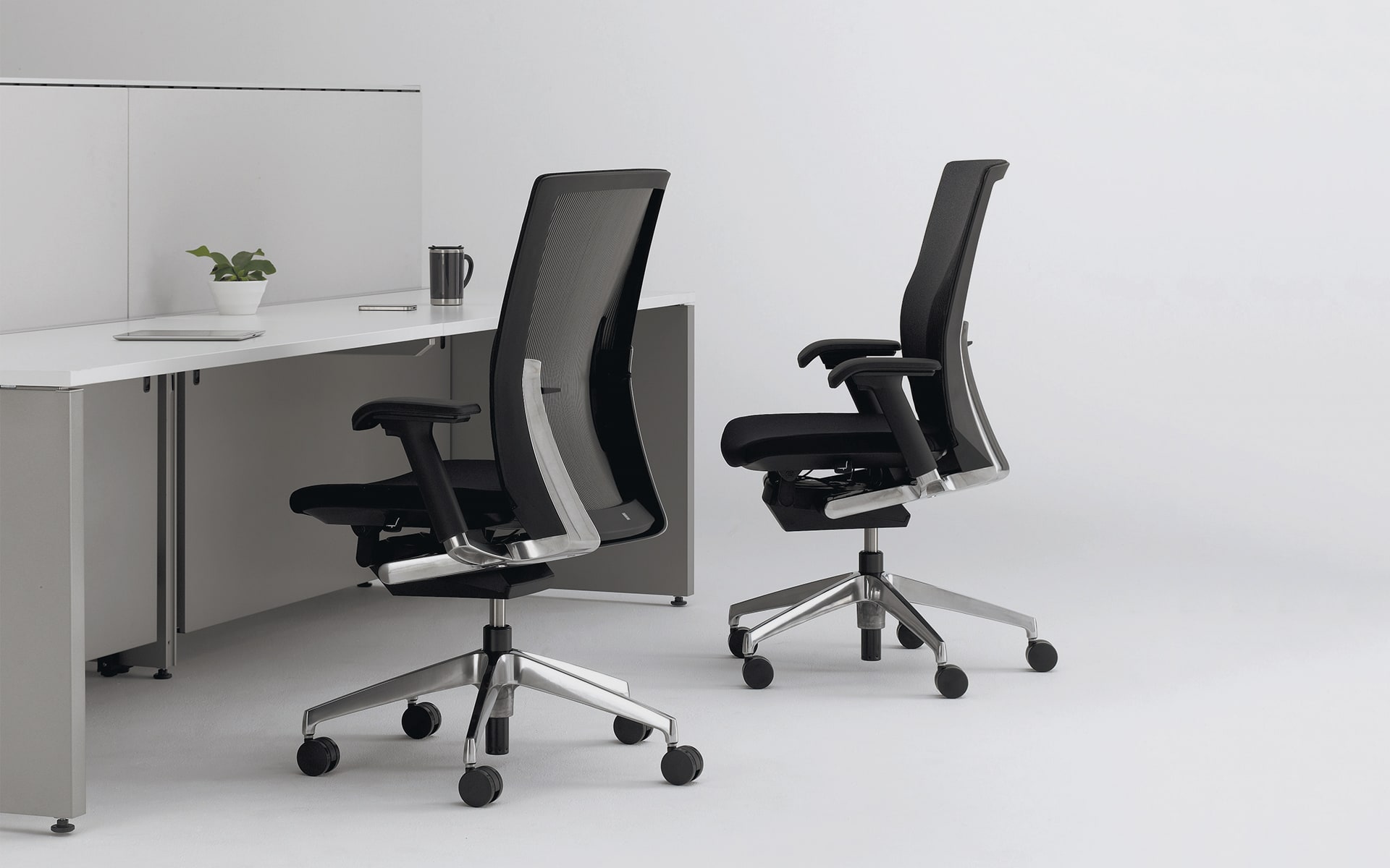 Two ITOKI Vento office chairs by ITO Design in black in puristic workspace