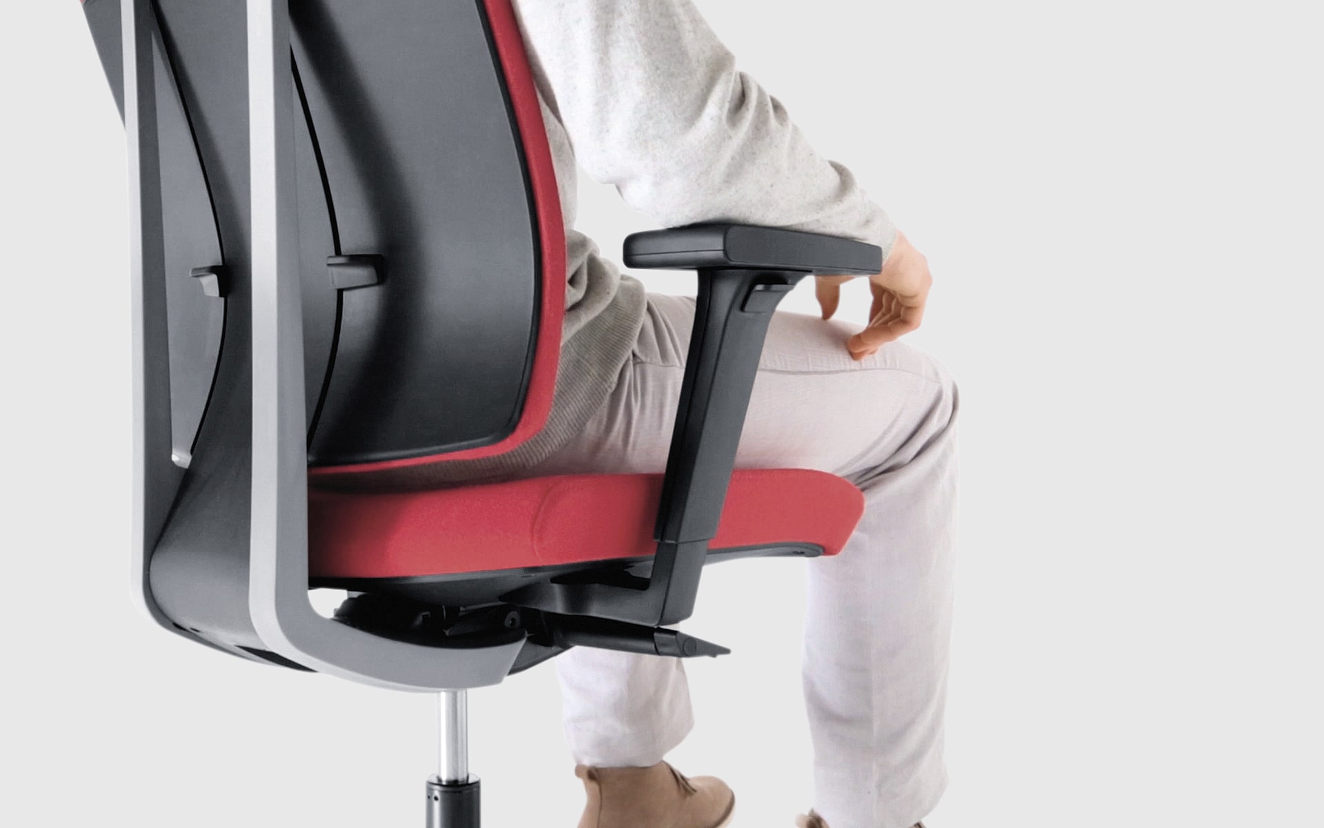 Person sits on Profim Xenon office chair by ITO Design with red upholstery