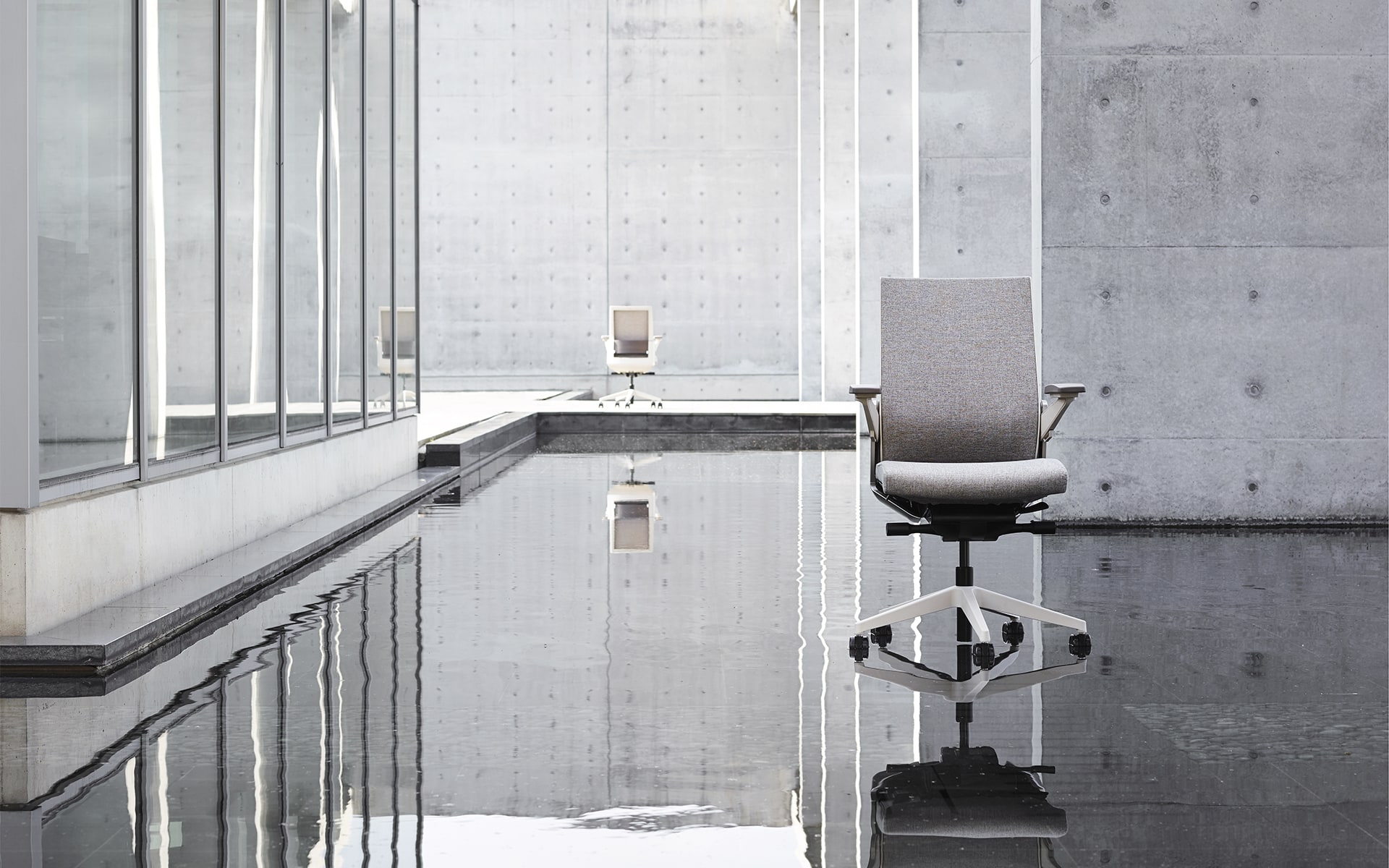 Gray Sidiz T80 executive office chairs by ITO Design on water surface in minimalist outdoor area