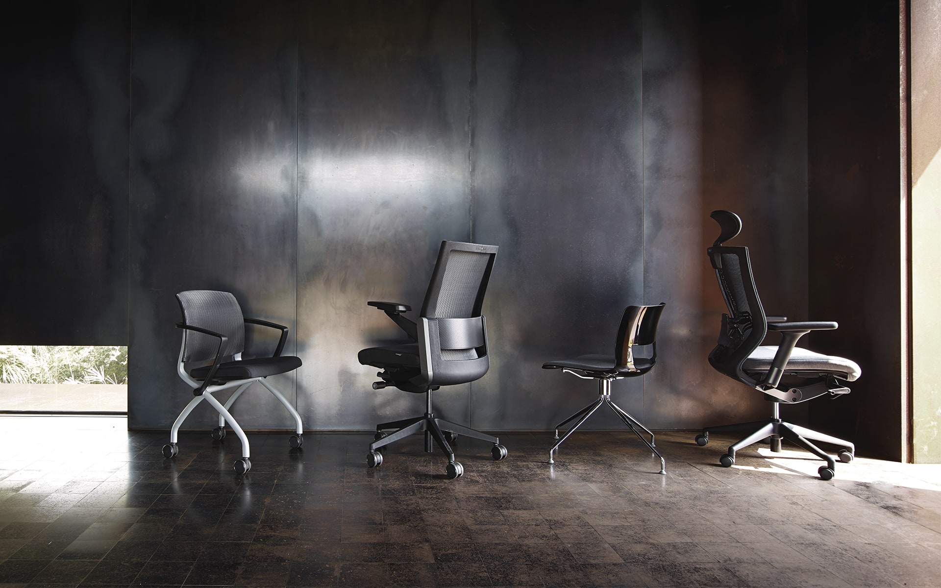 Black-gray Sidiz T80 executive office chair by ITO Design with other chairs in front of metal wall in empty room