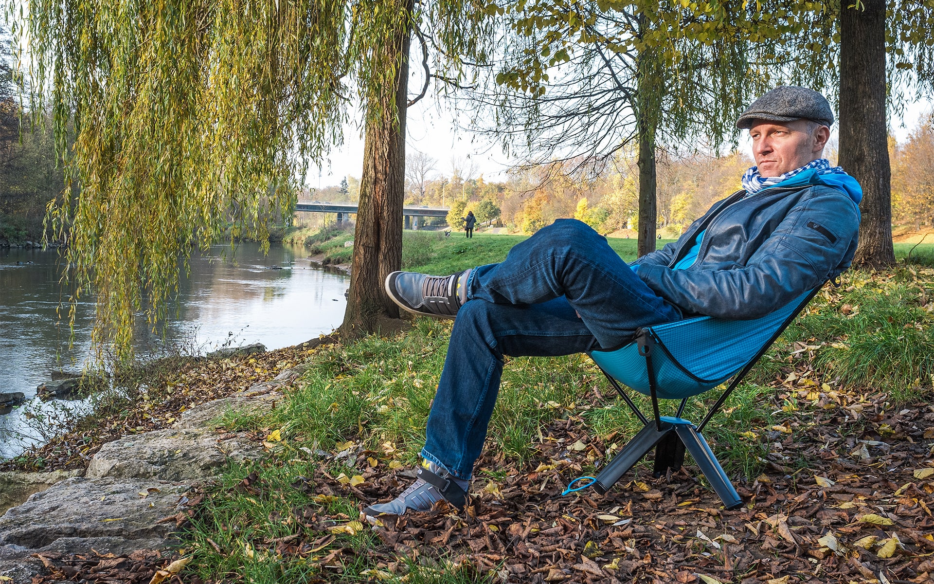Man sits in collapsable outdoor chair Therm-a-Rest Treo by ITO Design at a riverbank