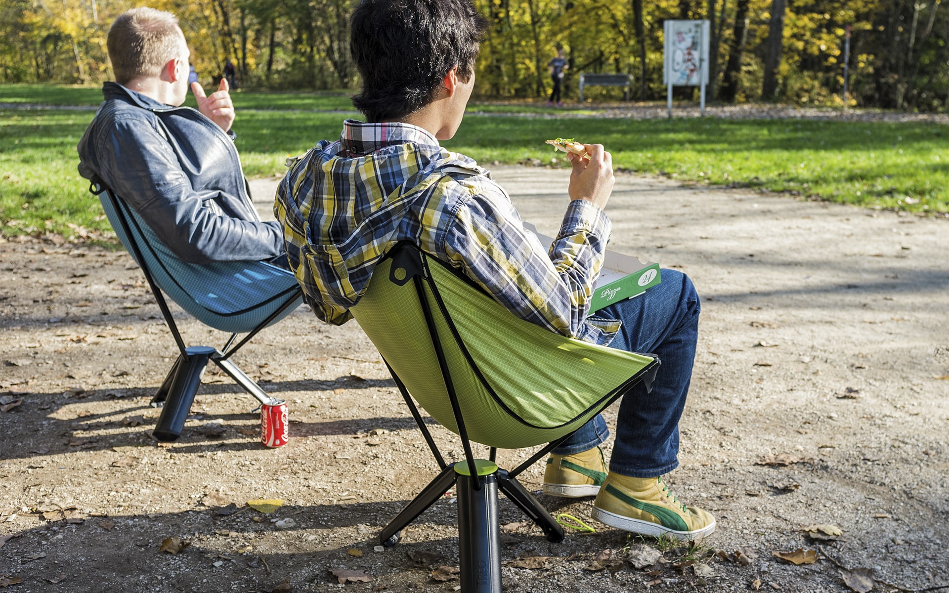 Men sit in park on collapsable outdoor chairs Therm-a-Rest Treo by ITO Design in blue and green