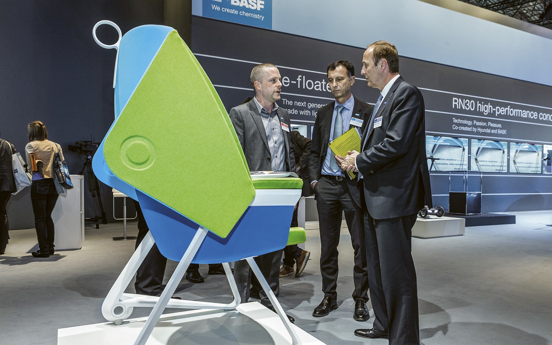 Three men in suits look at the BASF TeamUP chair by ITO Design at Orgatec 2016