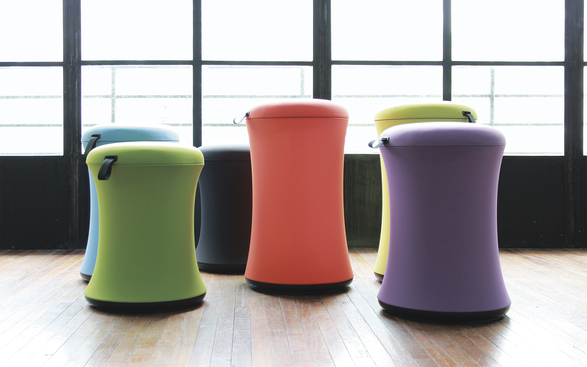 Six Uebobo stools, designed by ITO Design, in blue, grass-green, black, bright orange, yellow green and purple in bright room