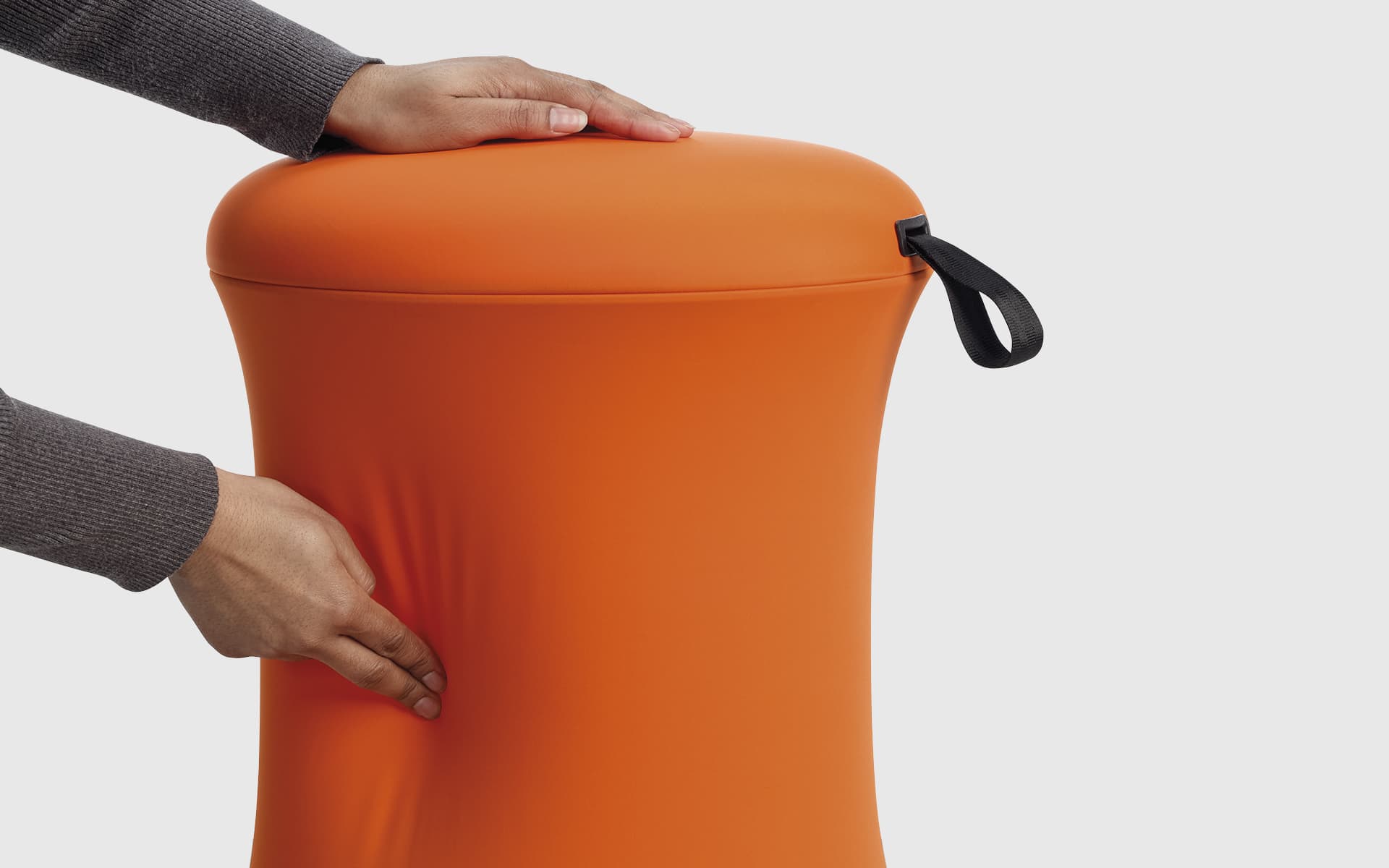 Nahaufnahme von Händen, die einen orangefarbenen UE Furniture Uebobo Hocker von ITO Design berühren