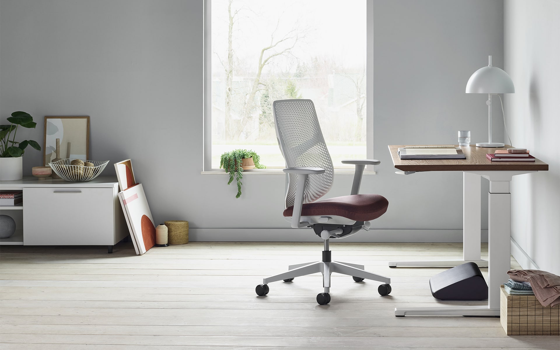 A Hermann Miller Verus office chair by ITO Design with light grey perforated backrest and berry-colored seat cushion in modern home office