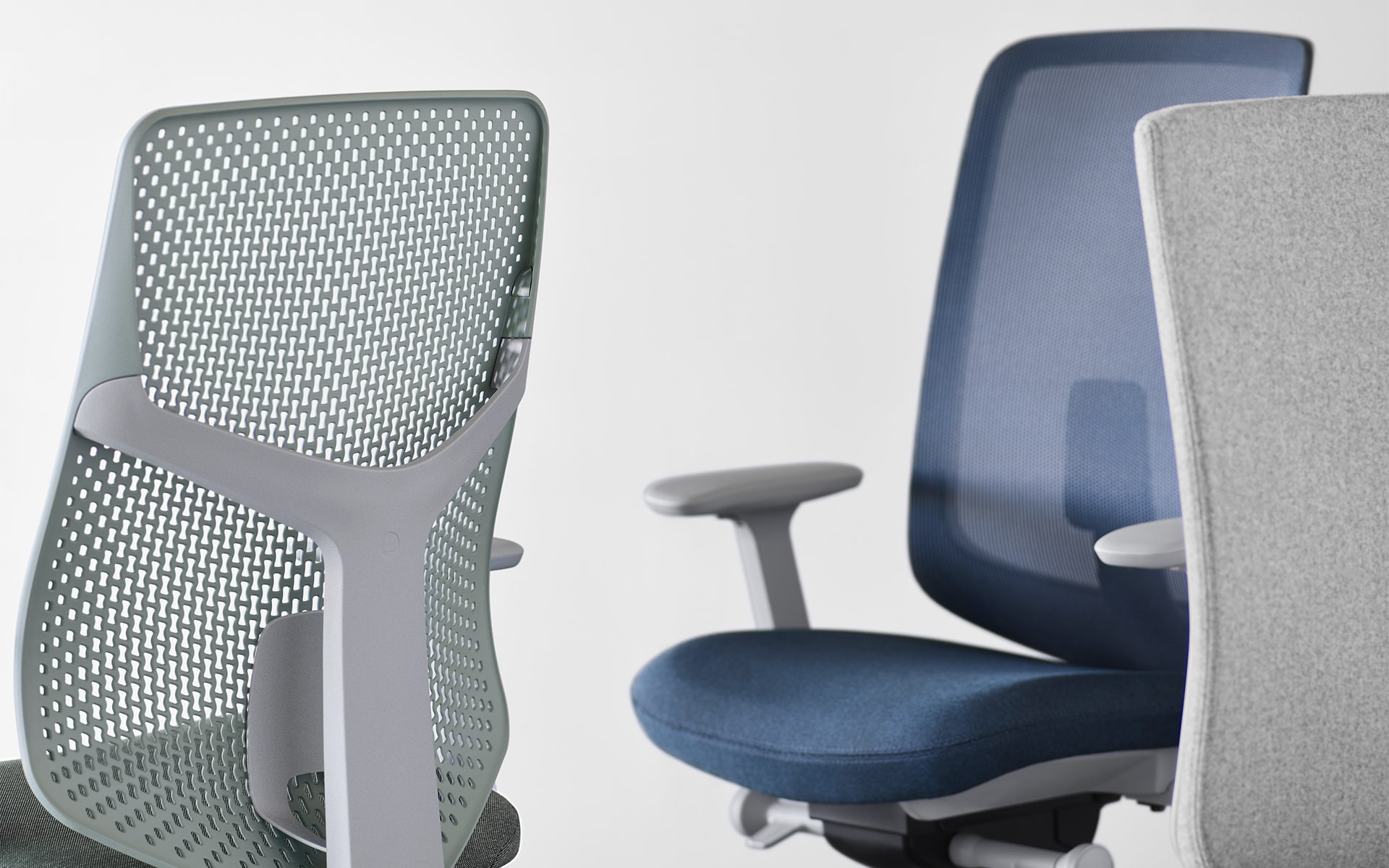 Close-ups of three chairs of the Hermann Miller Verus office chair family by ITO Design - one with the new perforated plastic backrest and two with other backrests