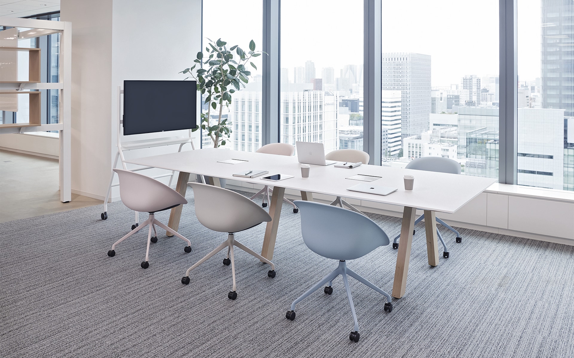 A bright conference room with six ITOKI Wan shell chairs by ITO Design in pale pink, white and pastel blue