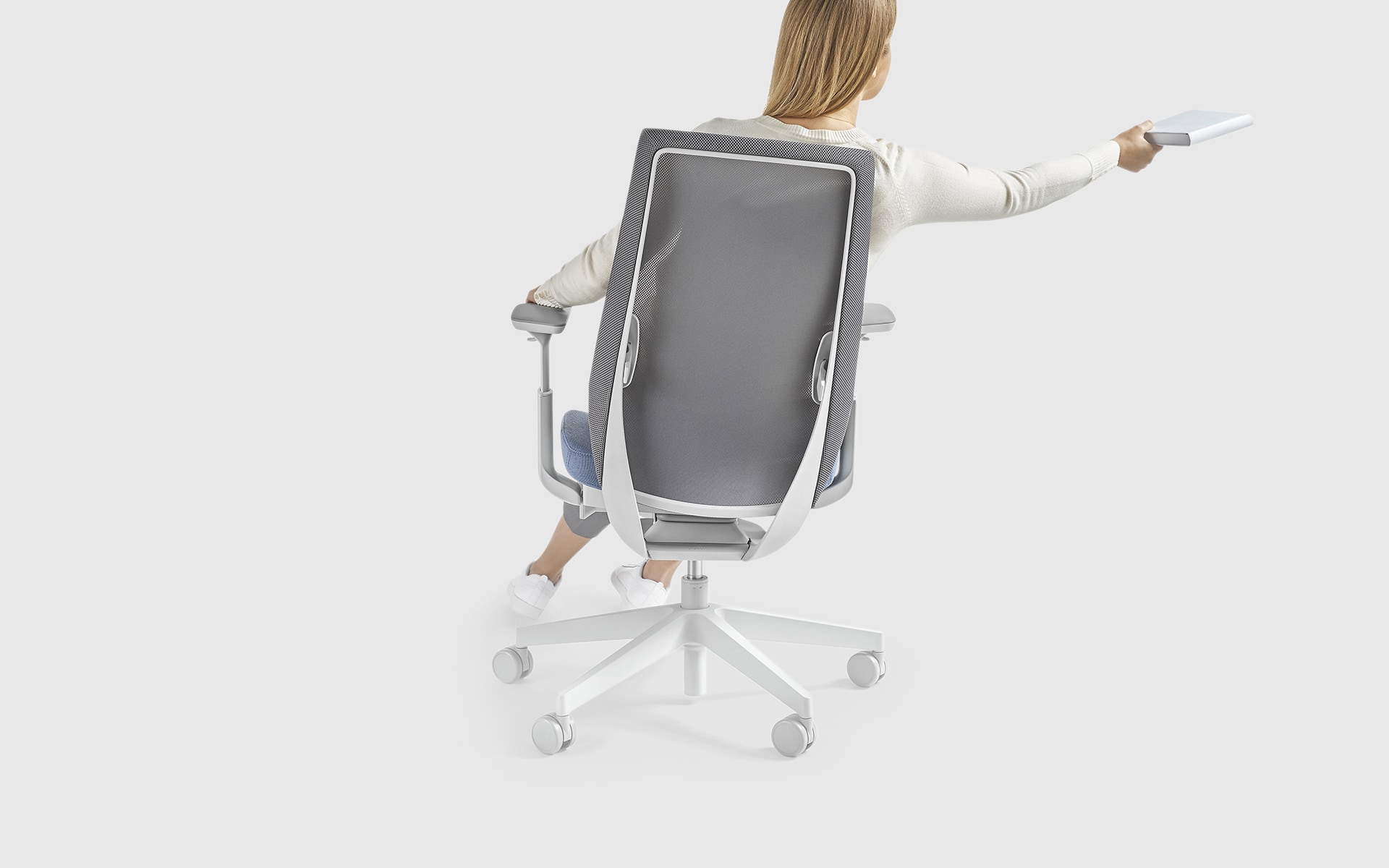 A woman sitting actively in a light grey Profim Accis Pro office chair by ITO Design